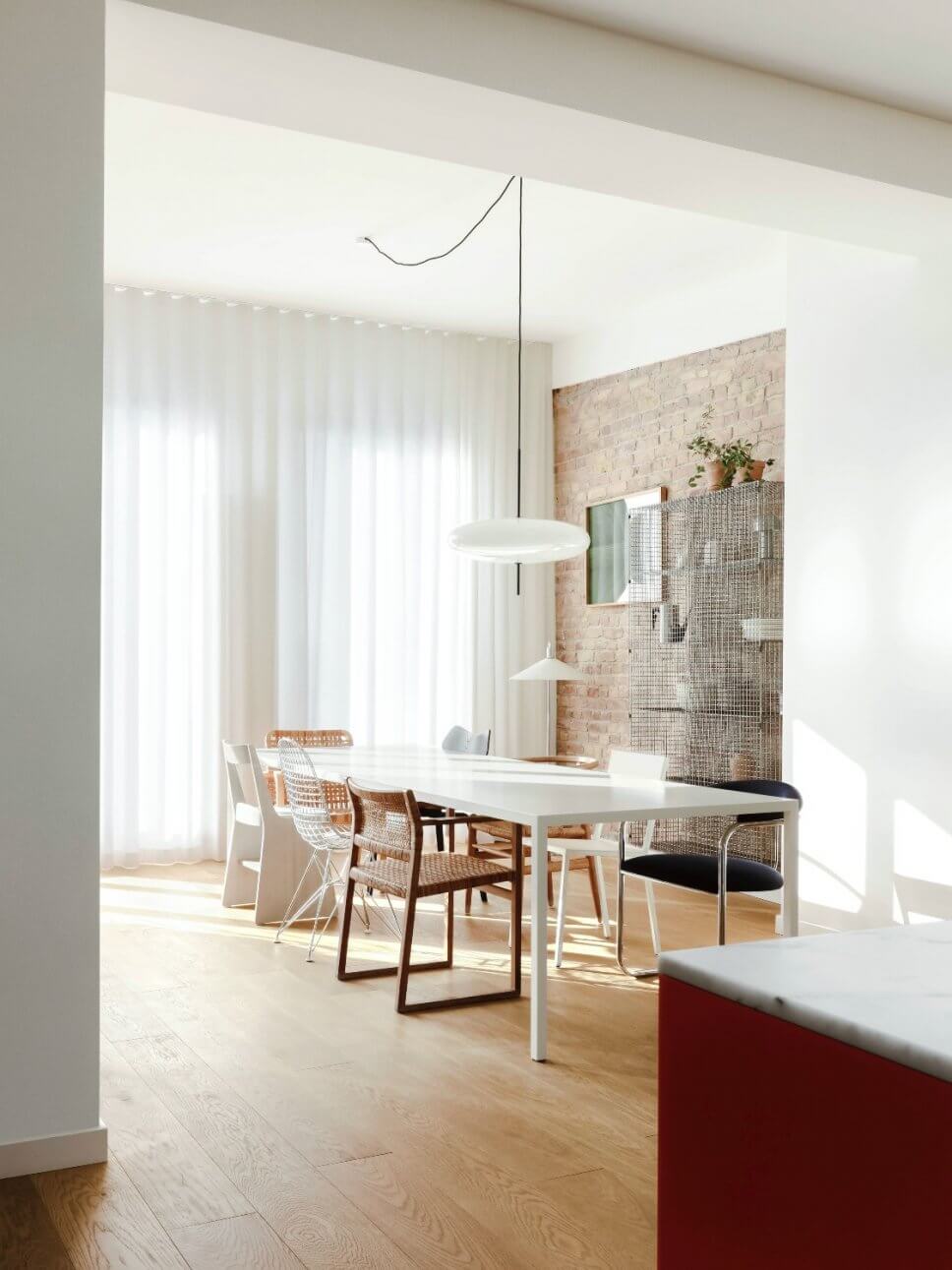 Modernes Esszimmer mit Backsteinwand, langem Tisch und unterschiedlichen Stühlen