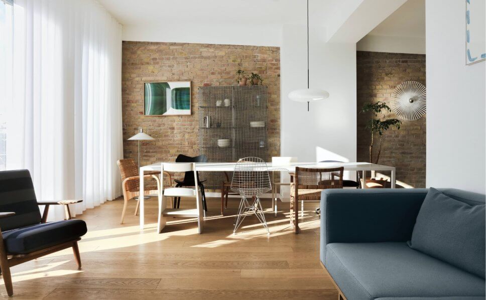 Modernes Esszimmer mit Backsteinwand, langem Tisch und unterschiedlichen Stühlen