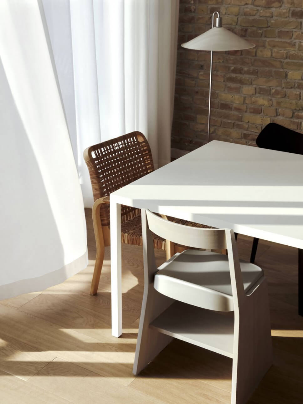 Modernes Esszimmer mit Backsteinwand, Esstisch und unterschiedlichen Stühlen