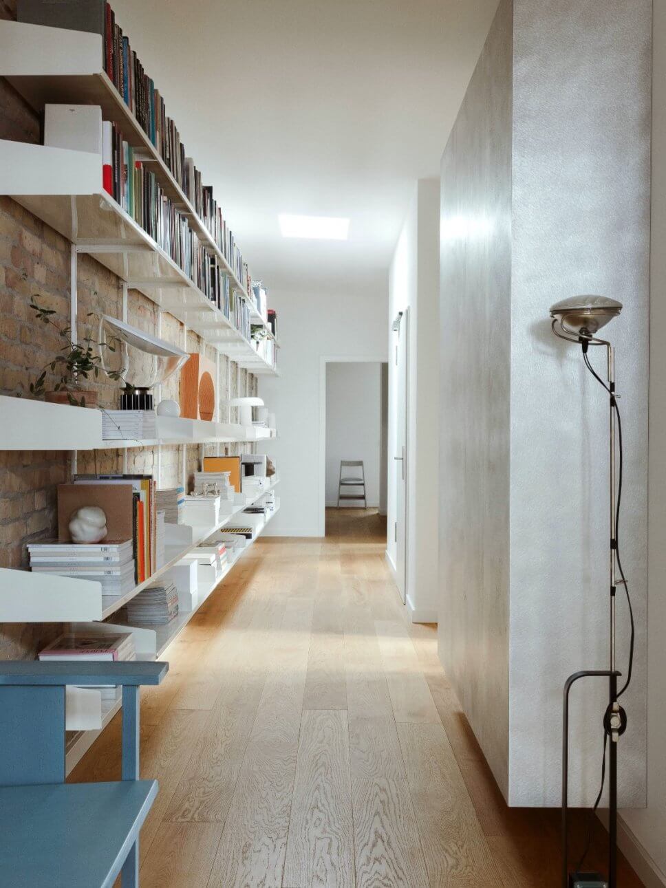 Langer Flur mit Regalwand und Stehlampe