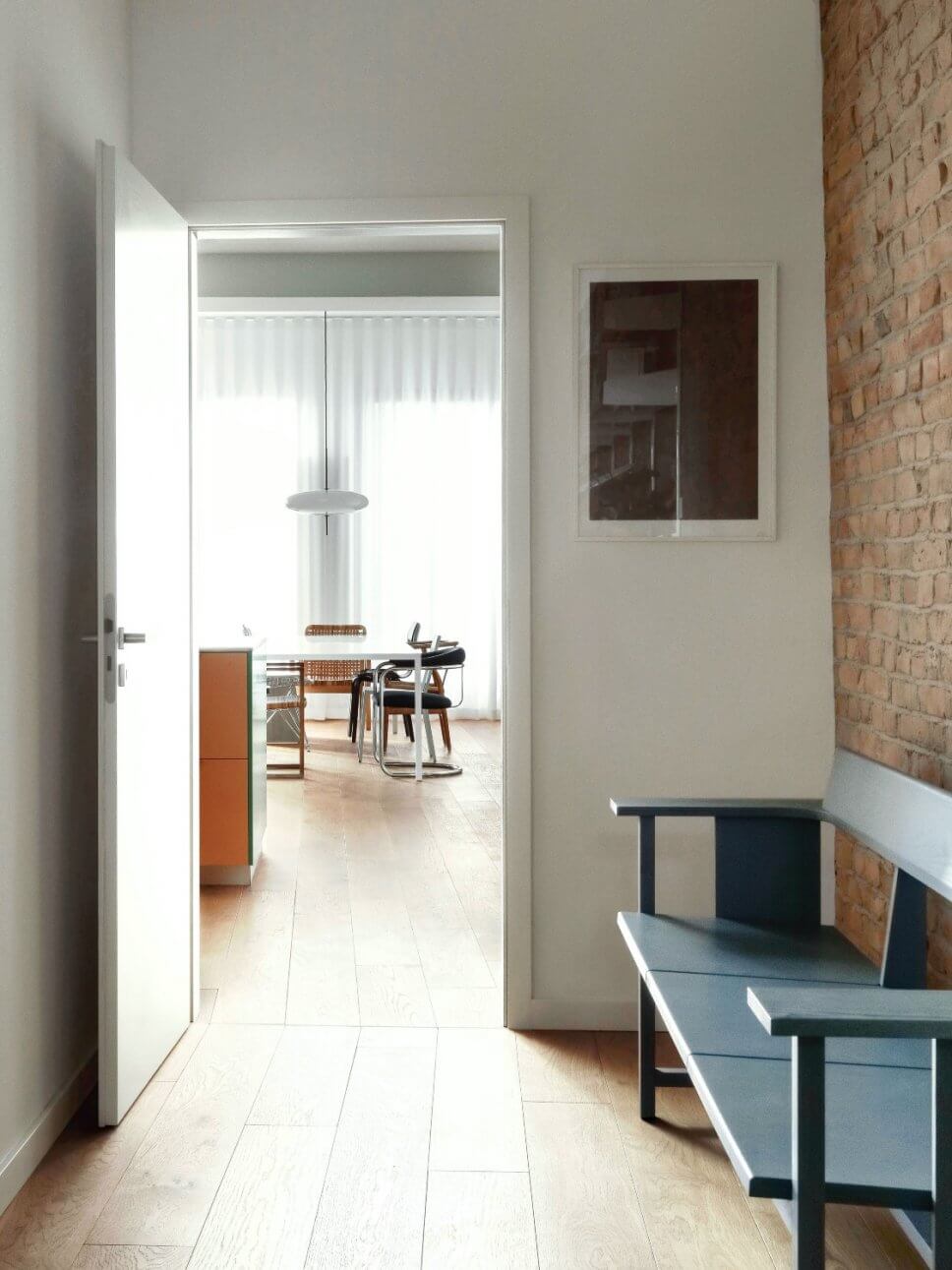 Moderne Wohnung mit Backsteinwand, Blick durch Tür von Flur ins Esszimmer