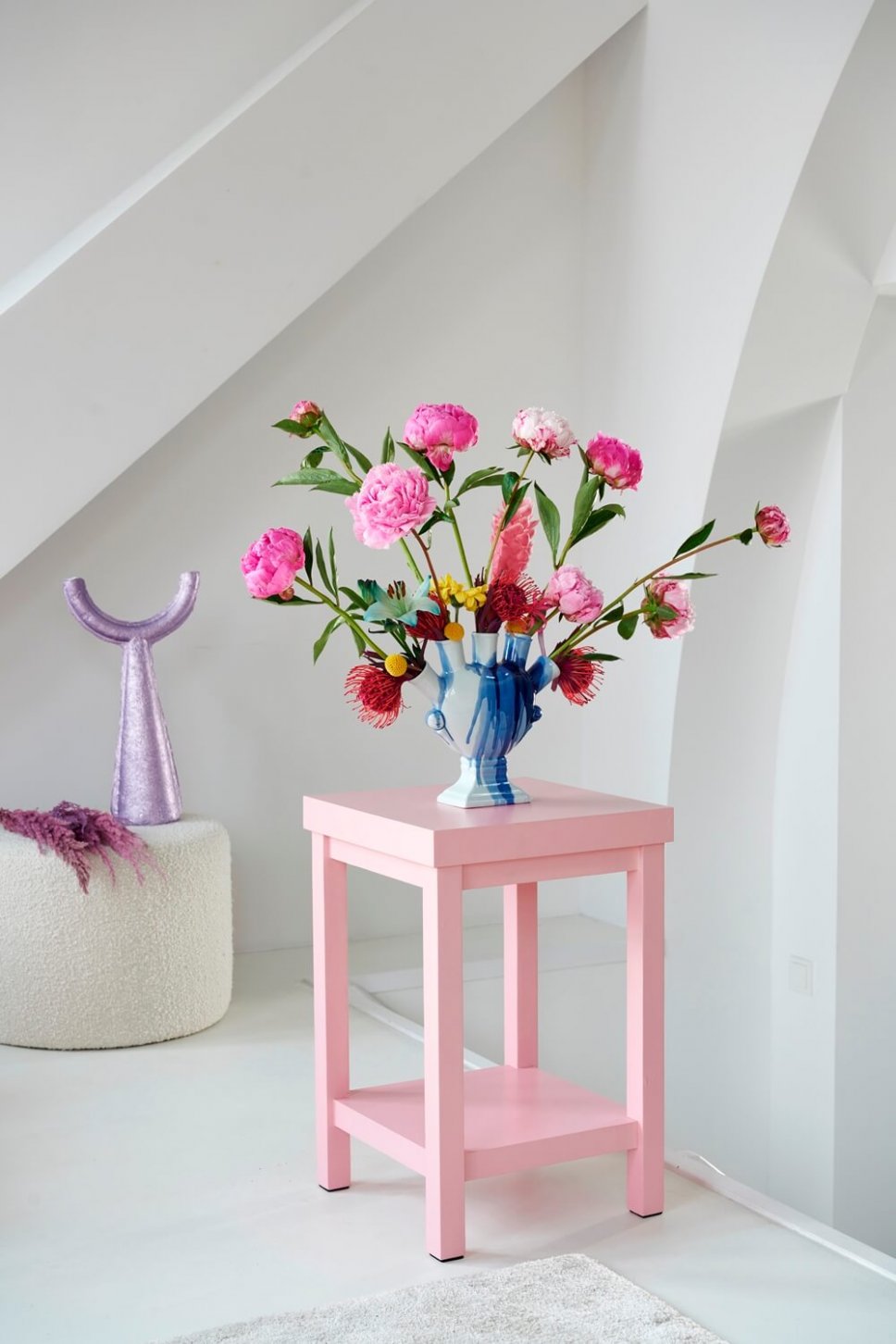 Moderner Wohnraum mit ausgefallener Vase, gefüllt mit Pfingstrosen