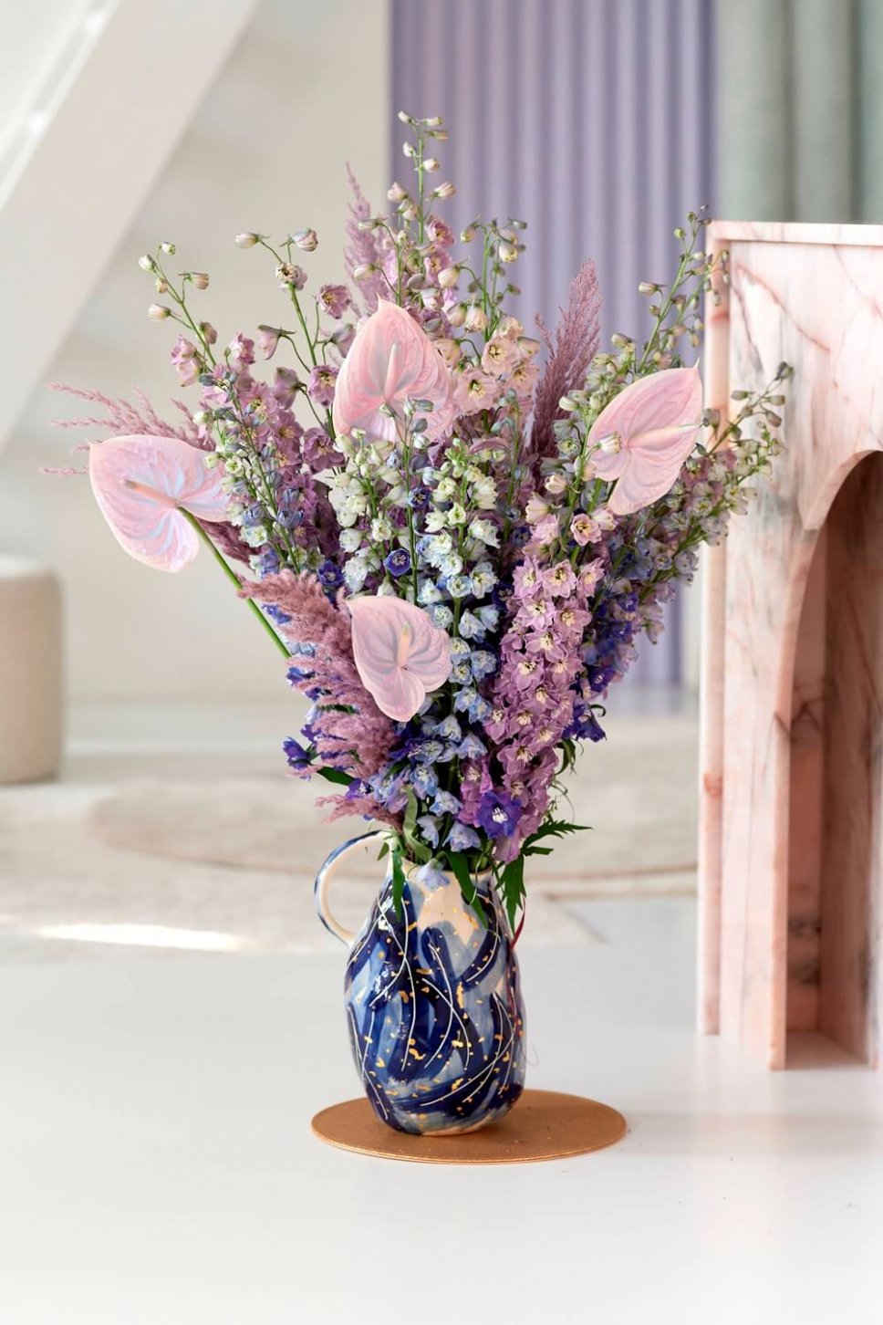 Moderner Wohnraum mit ausgefallener Vase, gefüllt mit Delphinium und Anthurien
