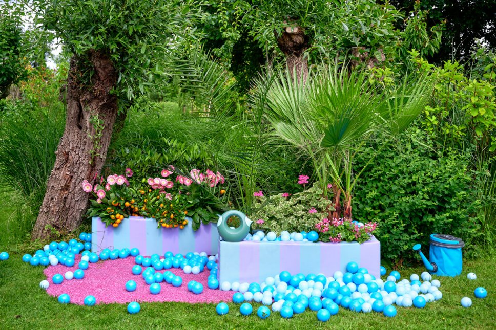 Garten mit bunten Blumenkasten gefüllt Gerbera, Zitruspflanzen, Pelargonien und Palmen