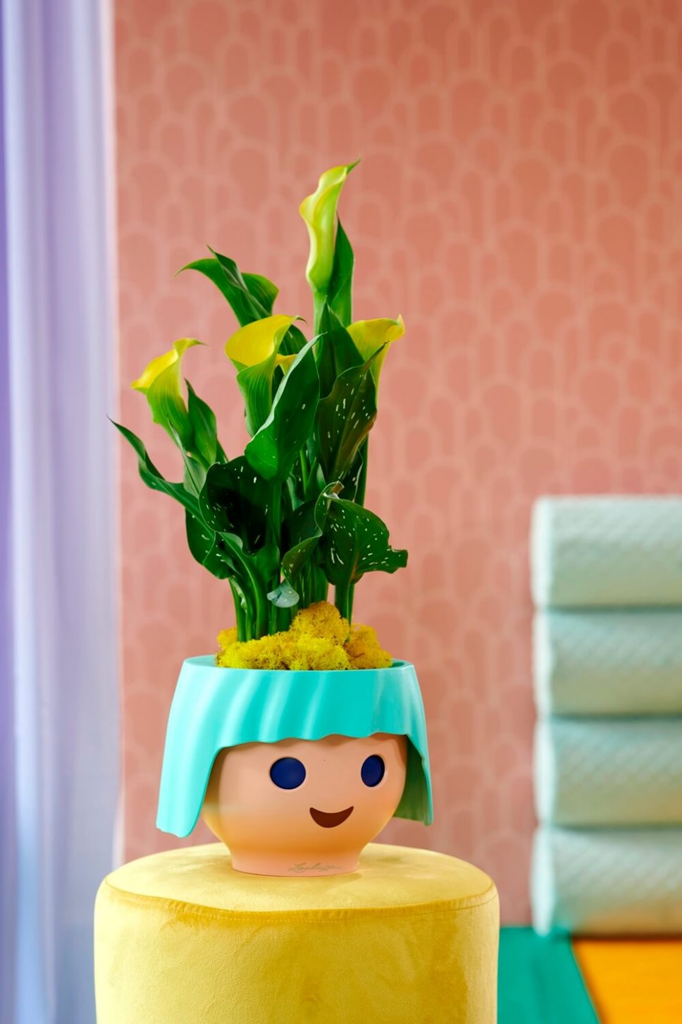 Moderner Wohnraum mit Blumenkasten in Form eines Playmobilkopfs, gefüllt mit Calla
