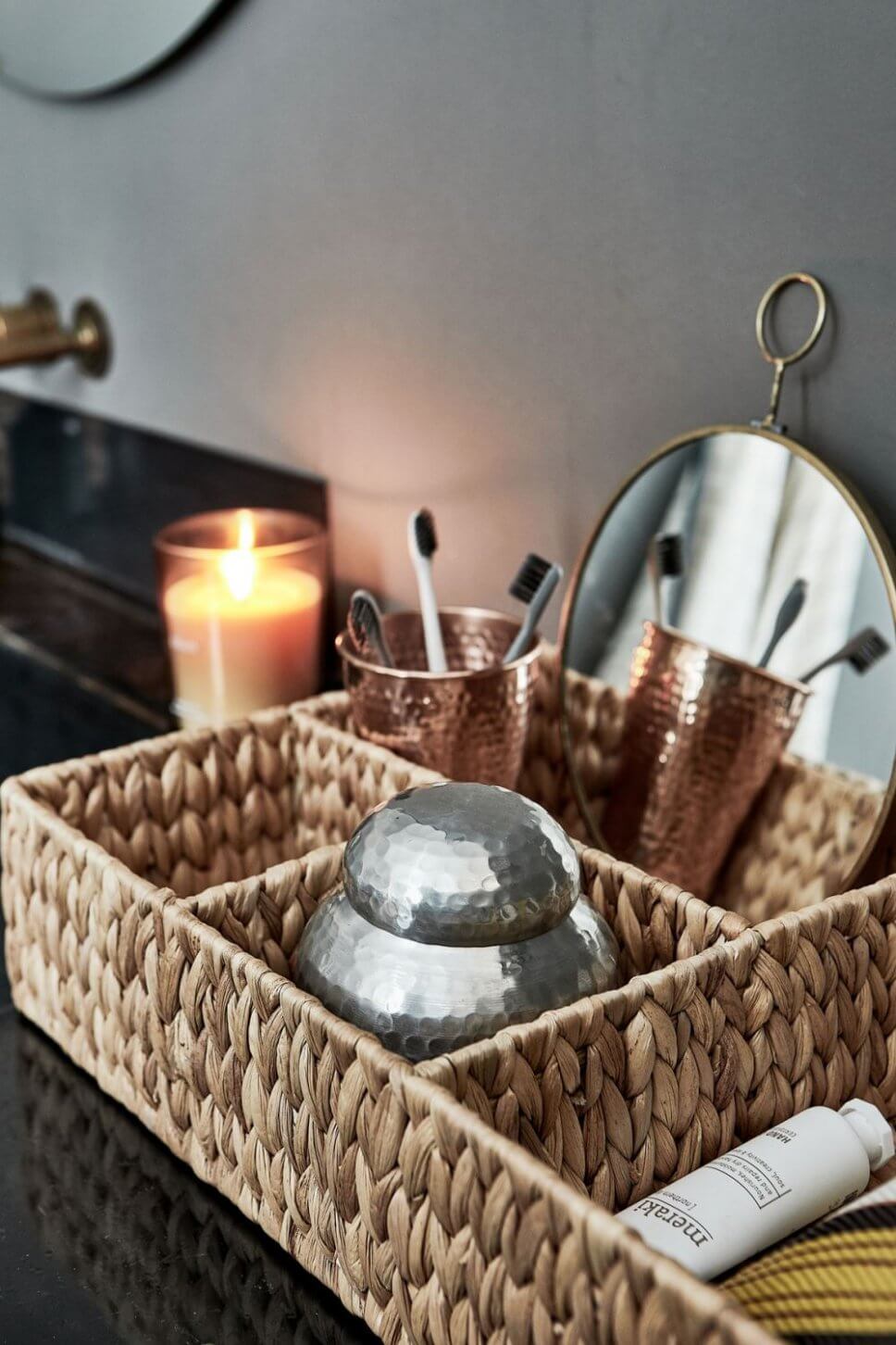 Korb mit Kupferbechern und Zahnbürsten im Badezimmer
