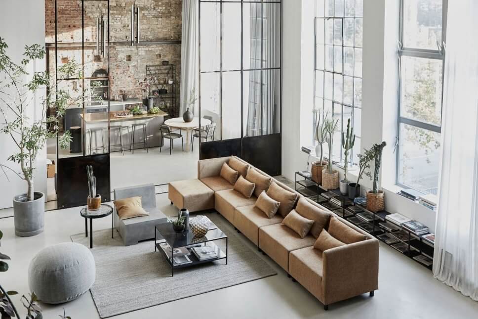 Sofas und Coffeetable im Industrieloft mit Blick durch hohe Stahlglastüren in offene Küche