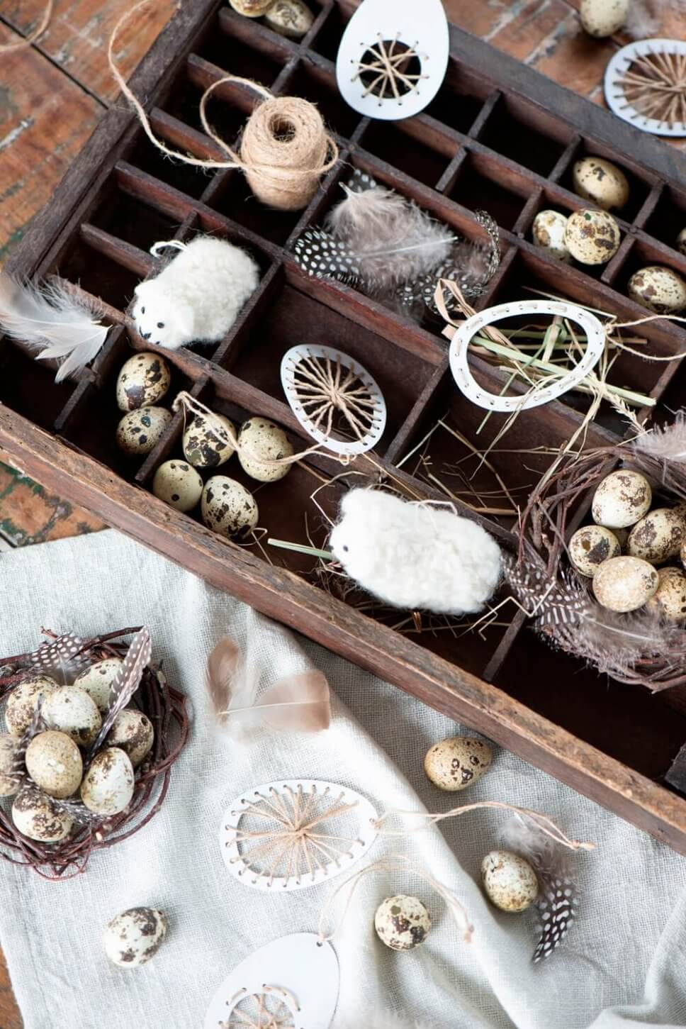 Wachteleier, Osterhänger und Wollschäfchen liegen im Setzkasten