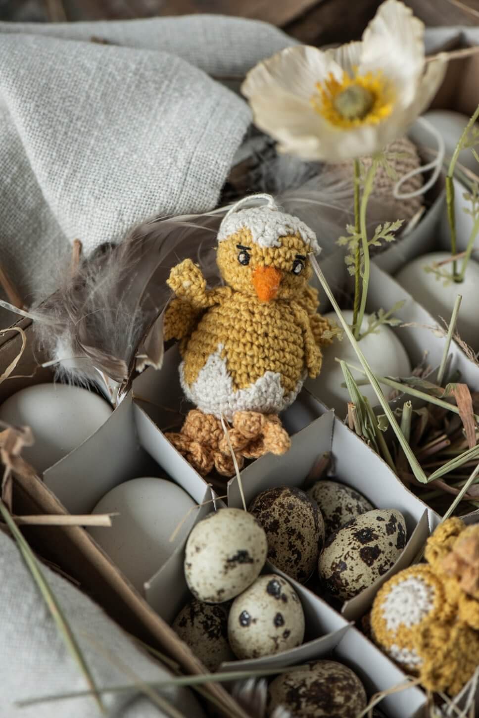 Wachteleier und gehäkelte Küken liegen im Karton