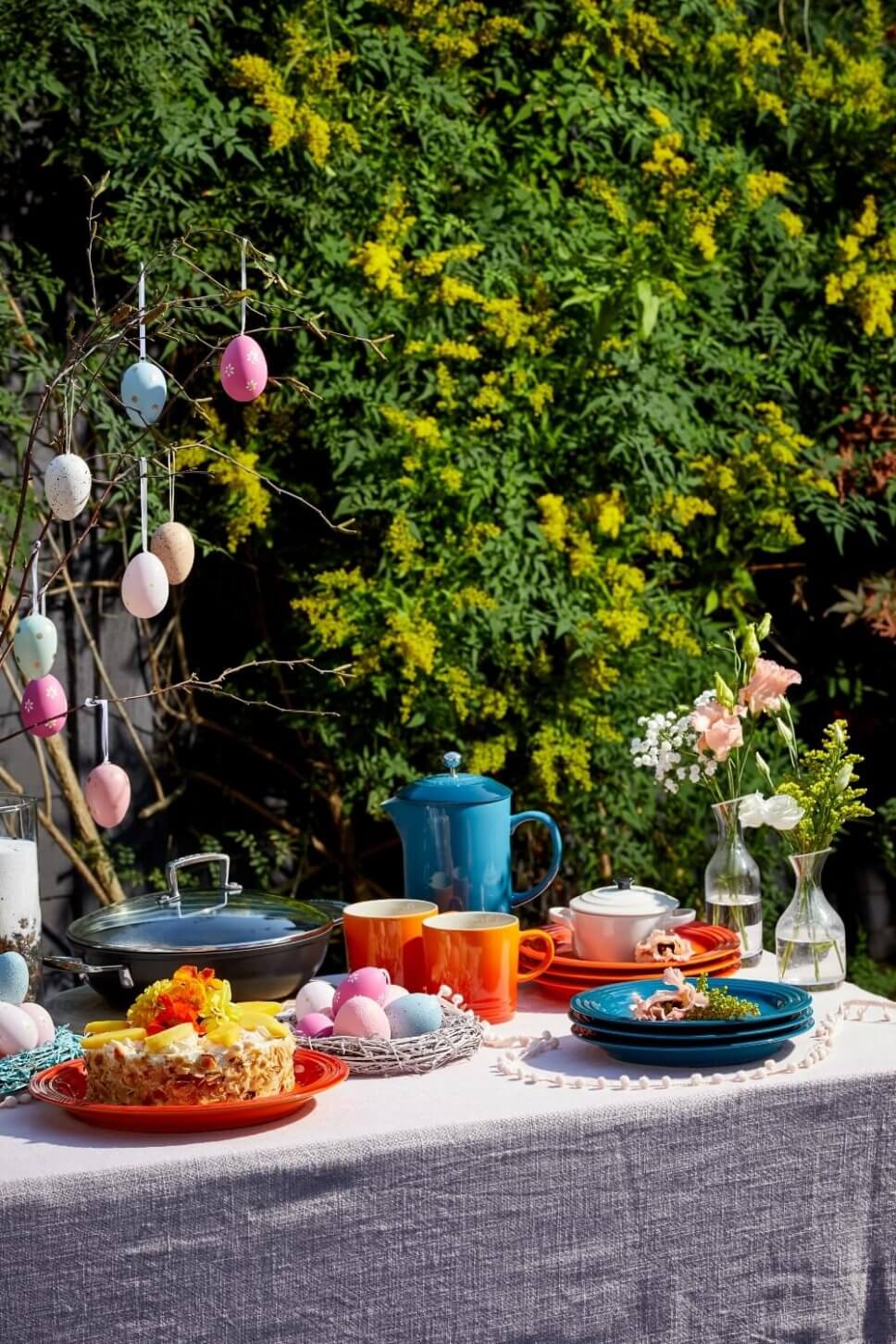 Österlich dekoriertes Buffet mit buntem Geschirr im Garten