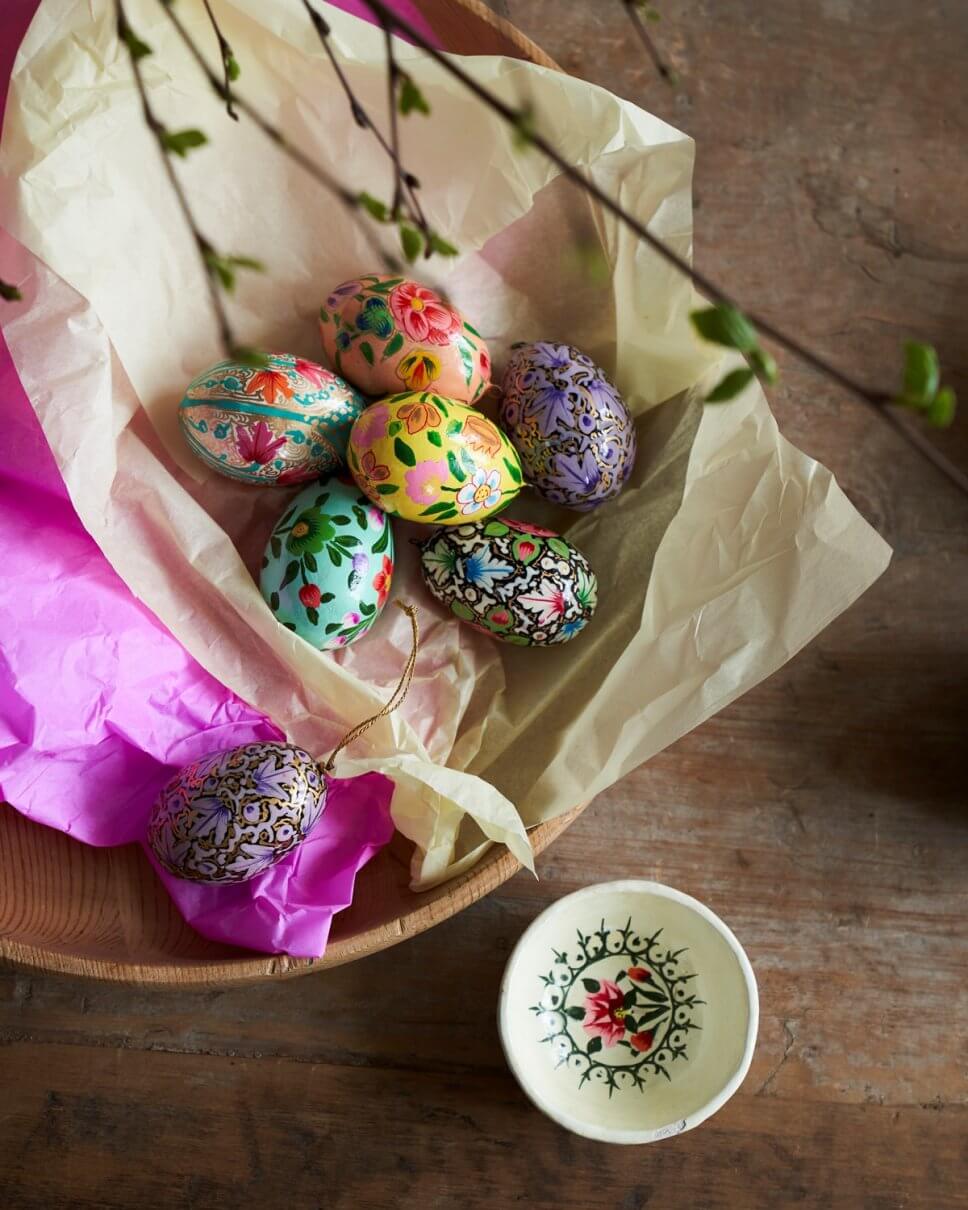 Bunt bemalte Ostereier liegen in Holzschale