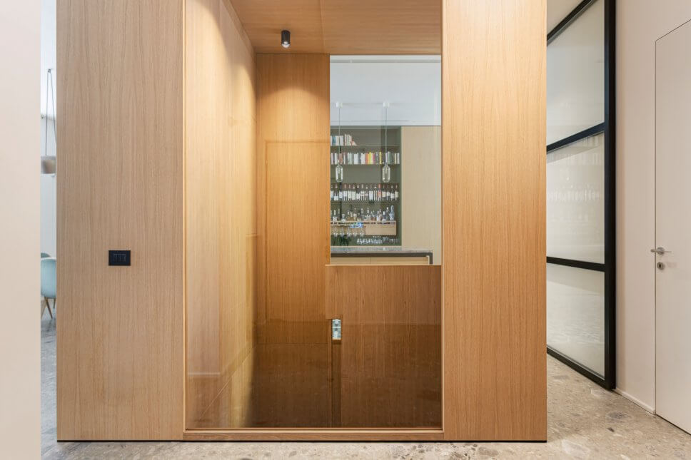 Treppenabgang aus hellem Holz mit Wandverkleidung aus gleichem Holz auf grauem Steinboden