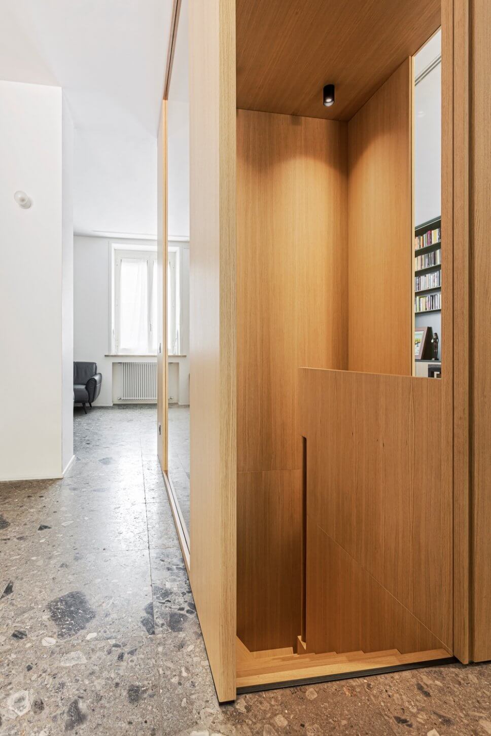 Treppenabgang aus hellem Holz mit Wandverkleidung aus gleichem Holz auf grauem Steinboden