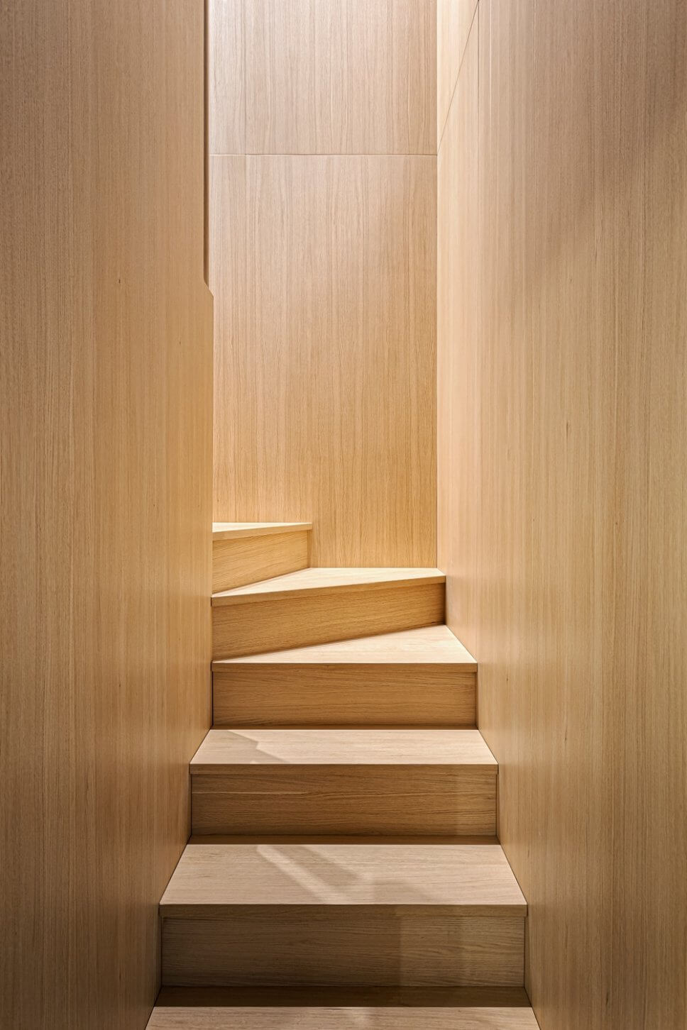 Treppe aus hellem Holz mit Wandverkleidung aus gleichem Holz