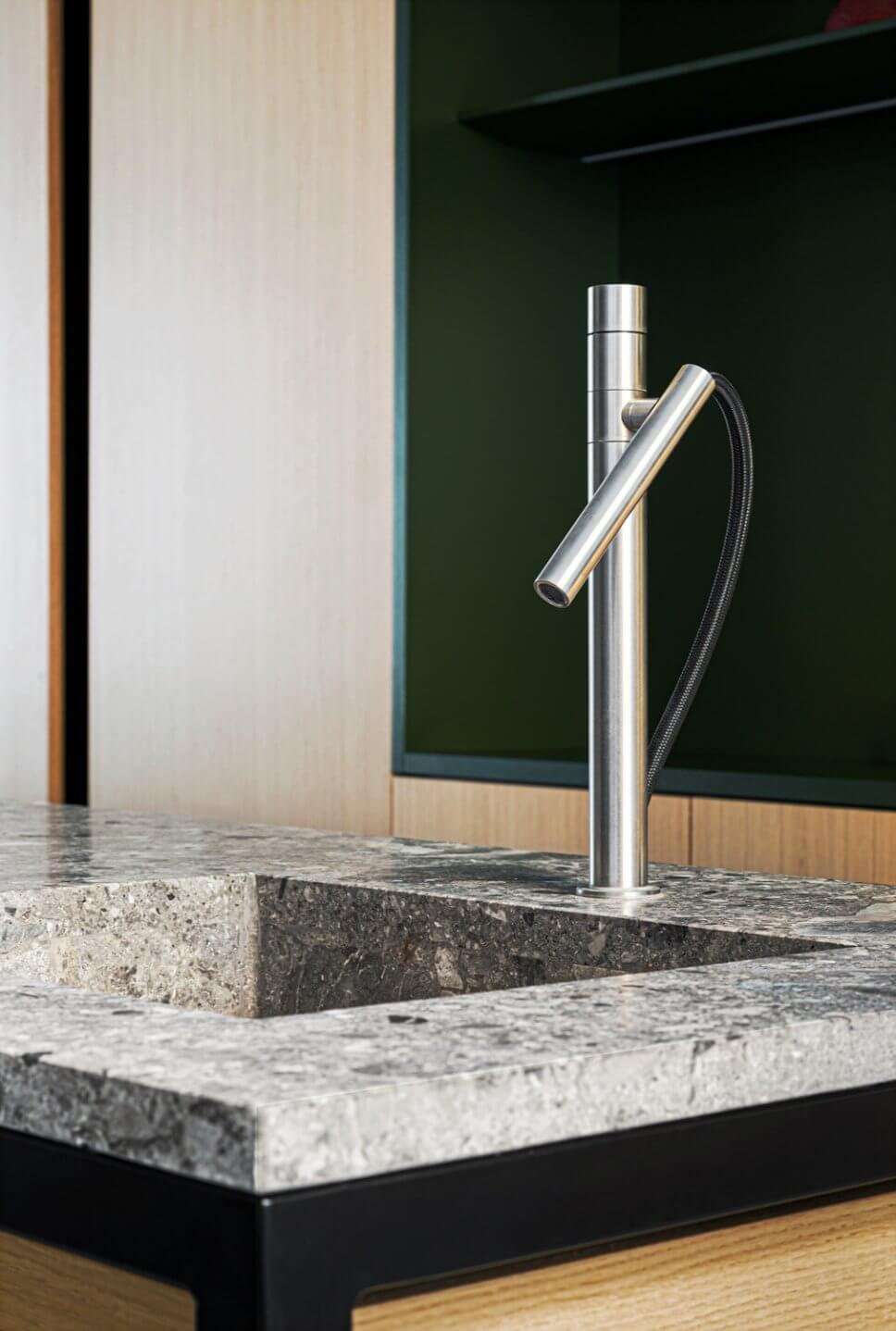 Formenreduzierter Edelstahl-Wasserhahn in moderner Wohnküche mit Marmor-Arbeitsplatte