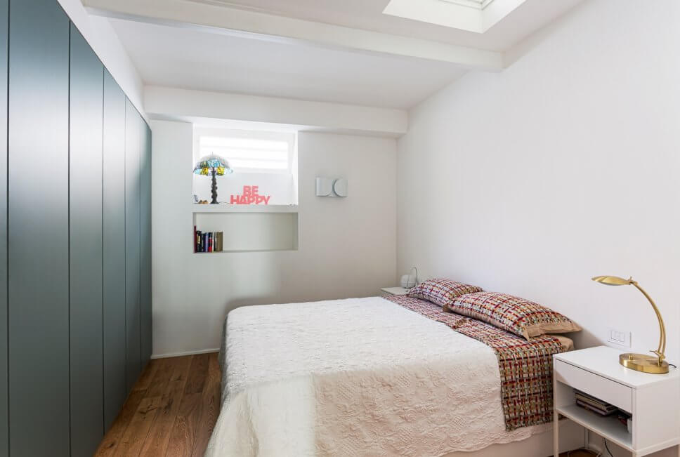 Modernes Schlafzimmer mit Einbauschrank, Doppelbett und kleinem Nachttisch mit Messing-Tischleuchte