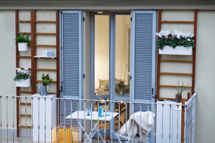 Mit Balkonkasten an Wandspalieren bepflanzter Balkon mit Klapptisch und Klappstuhl