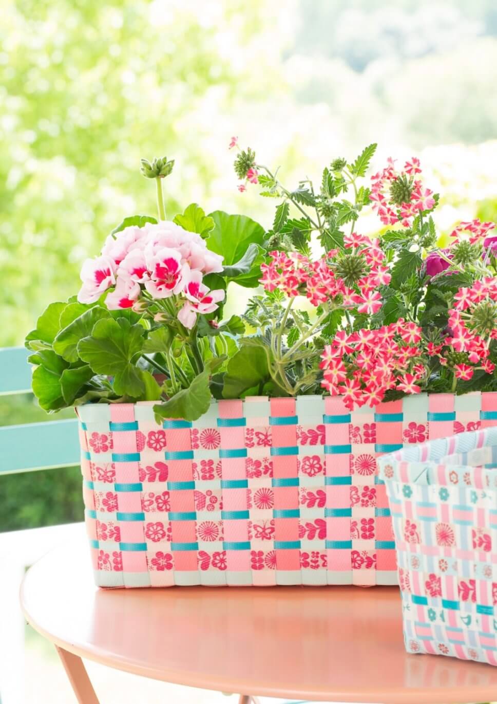 Üppig mit bunten Blumen bepflanzter Balkonkasten auf Gartentisch