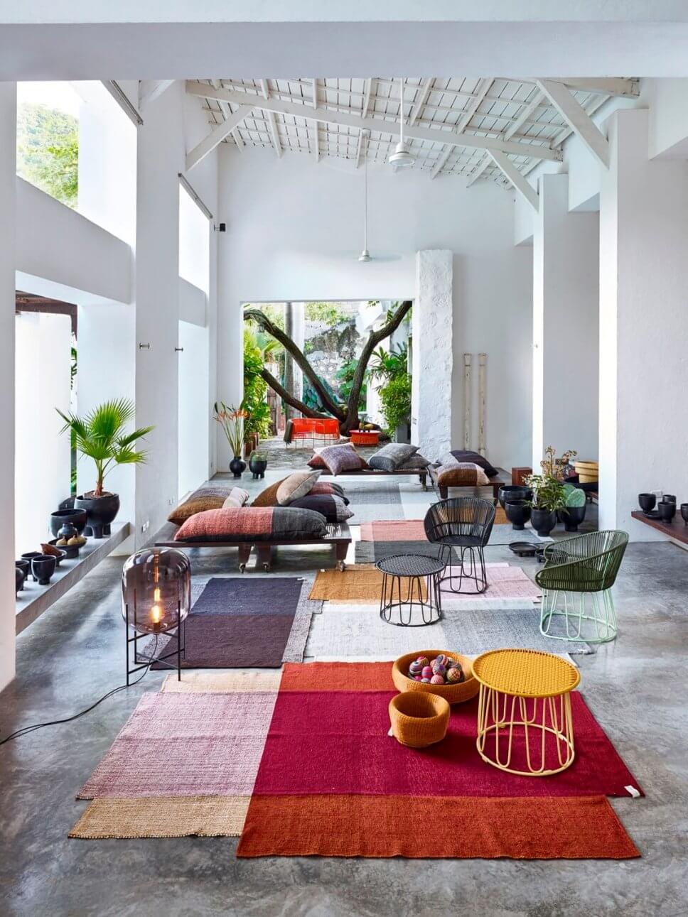 Offener Wohnraum bunten Teppichen, Kissen und mit Sesseln aus buntem Geflecht in einer kolumbianischen Casa