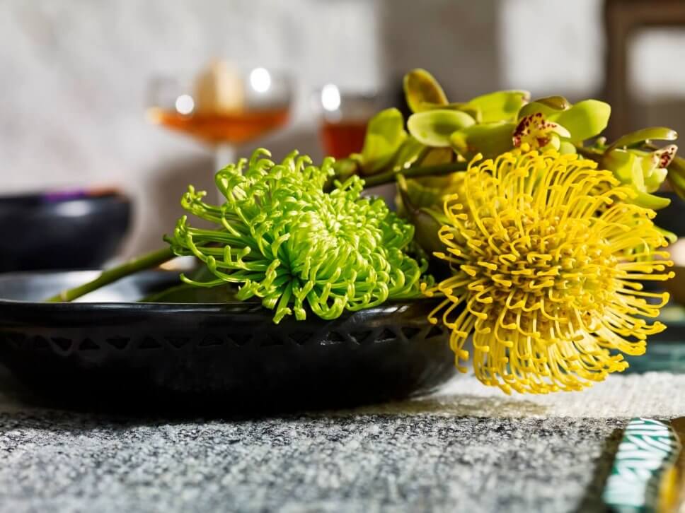 Schwarze Keramikschale mit exotischen gelben Blüten gefüllt