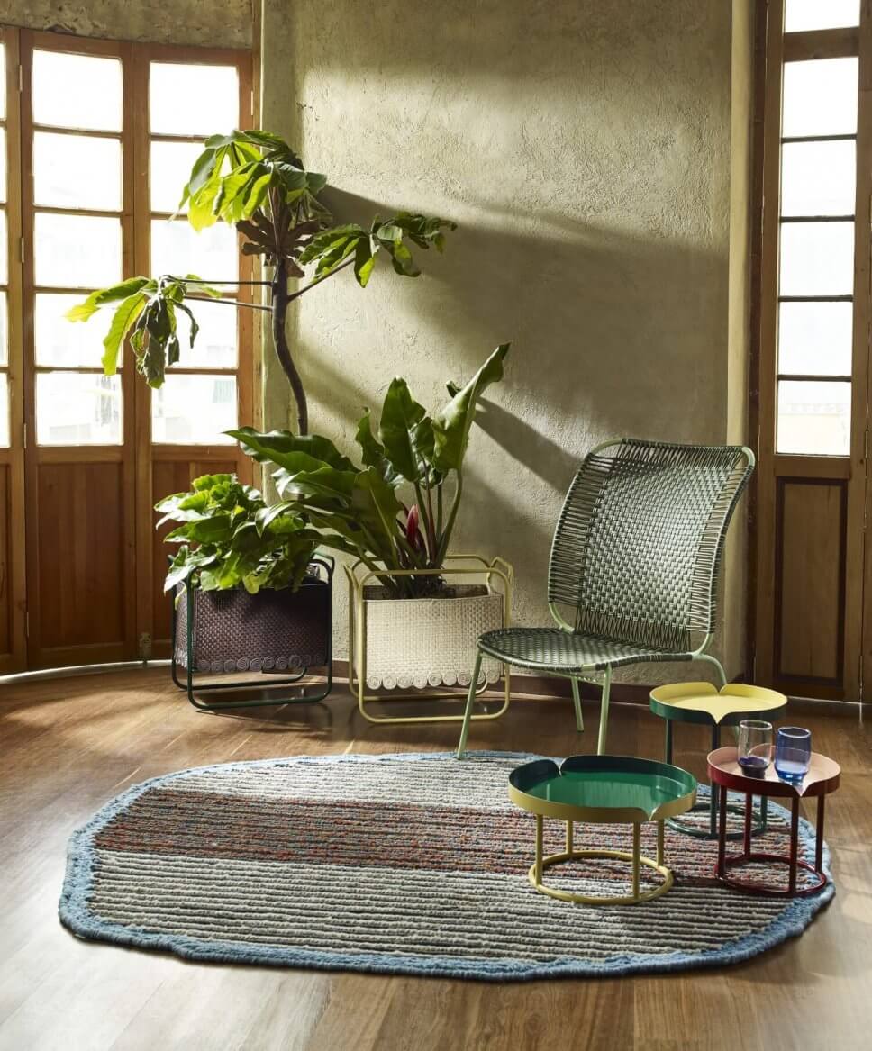 Wohnraum mit Sessel aus buntem Geflecht und einigen Coffeetable auf Teppich in einem kolumbianischen Kolonialhaus