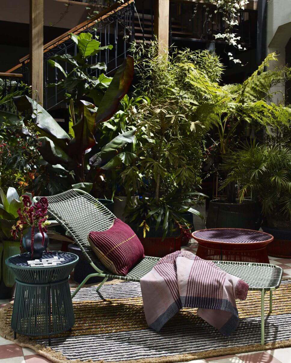 Sonnenliege auf Teppich im üppig bepflanzten Patio eines kolumbianischen Kolonialhauses