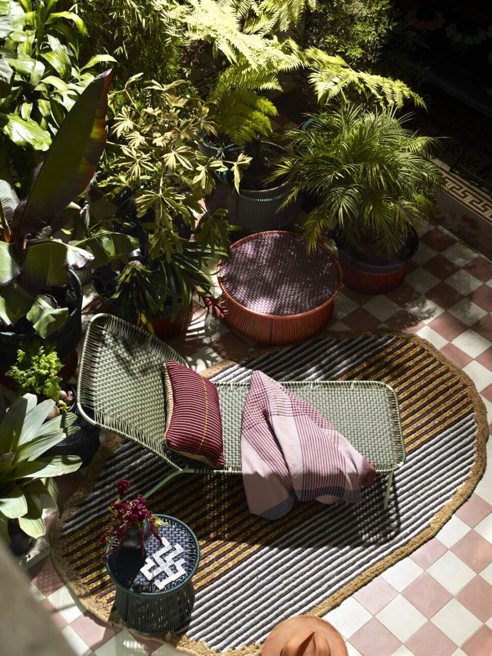 Sonnenliege auf Teppich im üppig bepflanzten Patio eines kolumbianischen Kolonialhauses