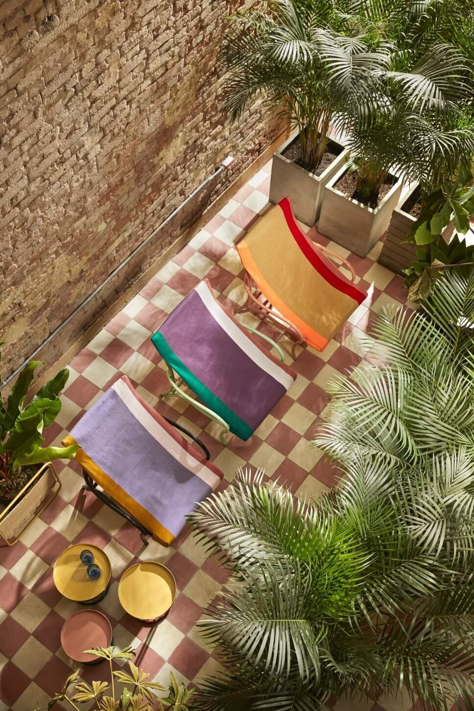 Drei bunte Sonnenliegen im üppig bepflanzten Patio eines kolumbianischen Kolonialhauses