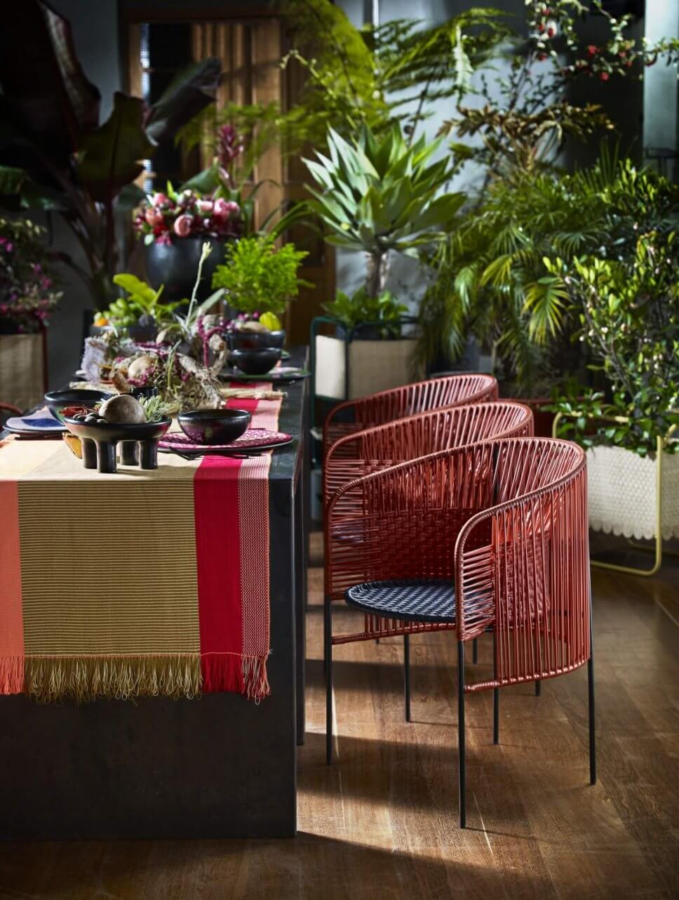 Gedeckter Tisch mit bunten Geflechtstühlen im üppig bepflanzten Raum eines kolumbianischen Kolonialhauses