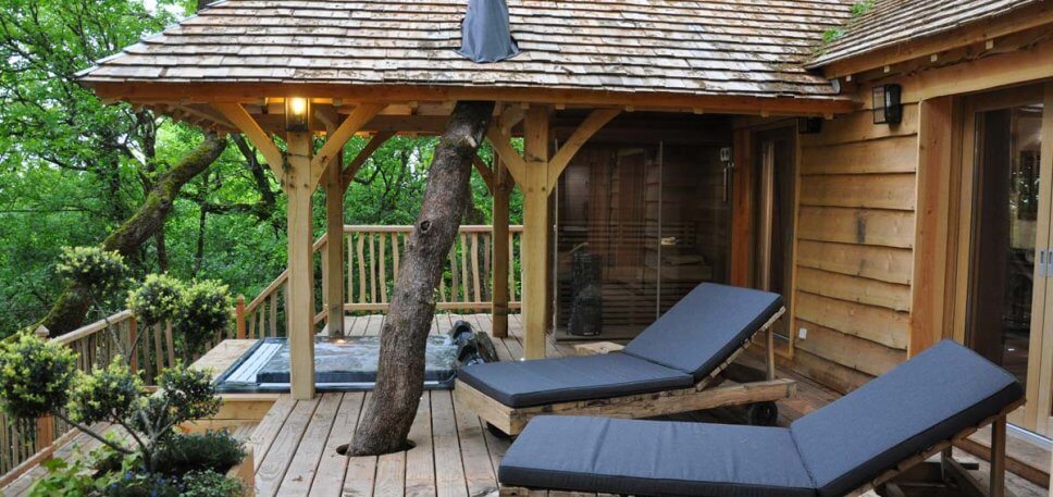 Terrasse mit Whirlpool und Sonnenliegen an einem Baumhaus