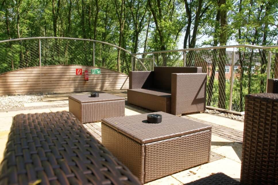 Terrasse mit Sessel und Couchtischen aus Rattan an einem Baumhaus
