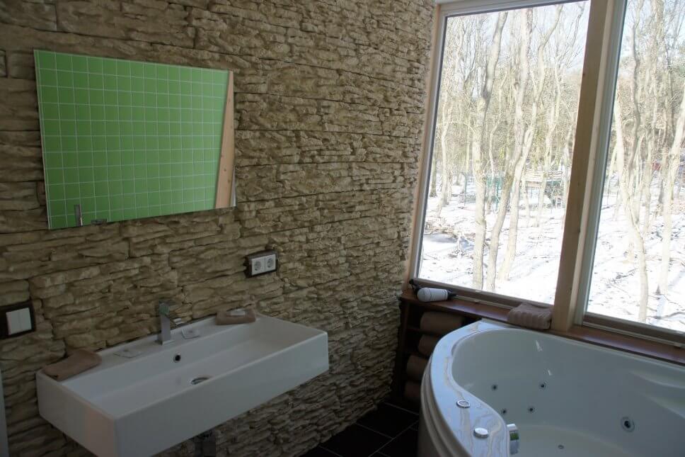 Badezimmer mit Waschbecken und einer Whirlpool-Badewanne in einem geräumigen Baumhaus