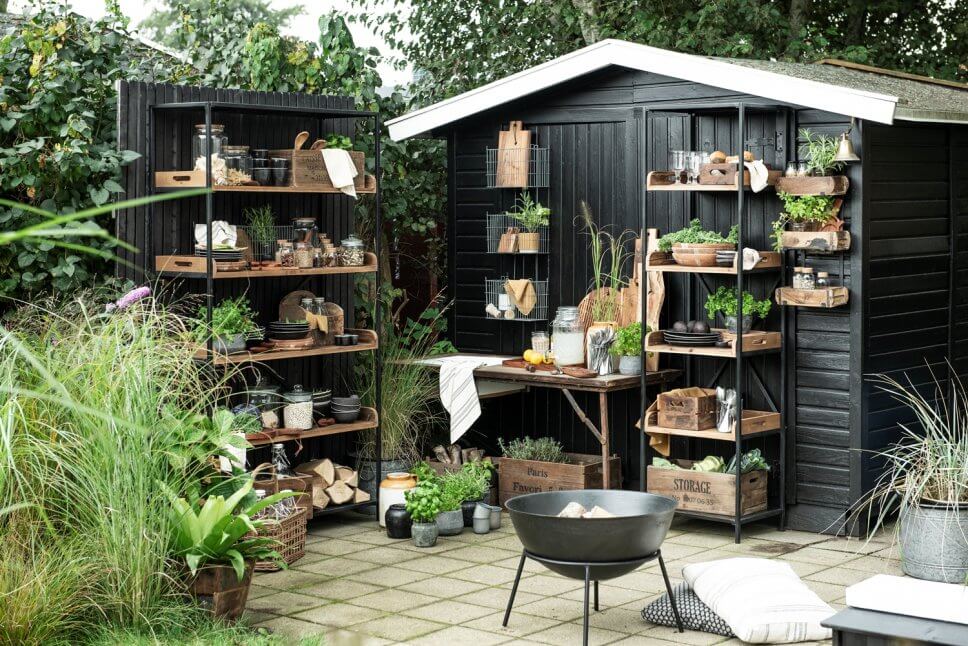 Rustikale Outdoorküche Rustikale Outdoorküche mit Holztisch, Metallregalen und vielen Kübelpflanzen