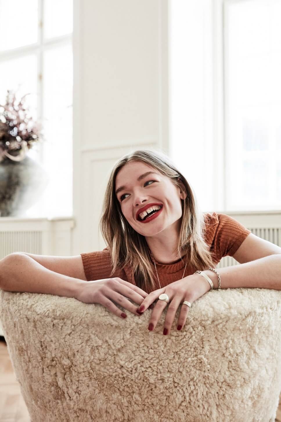 Junge Frau sitzt auf mit Schaffell bezogenem Sessel