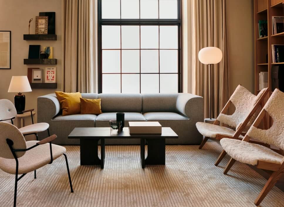 Modernes Wohnzimmer mit schlichtem Sofa und drei mit Schaffell bezogenem Sesseln