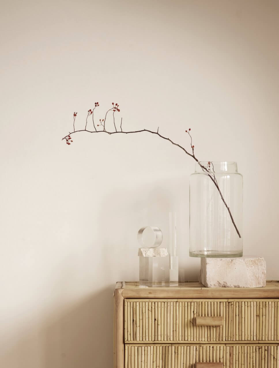 Zweig in einem großen Glas steht auf Bambus-Kommode