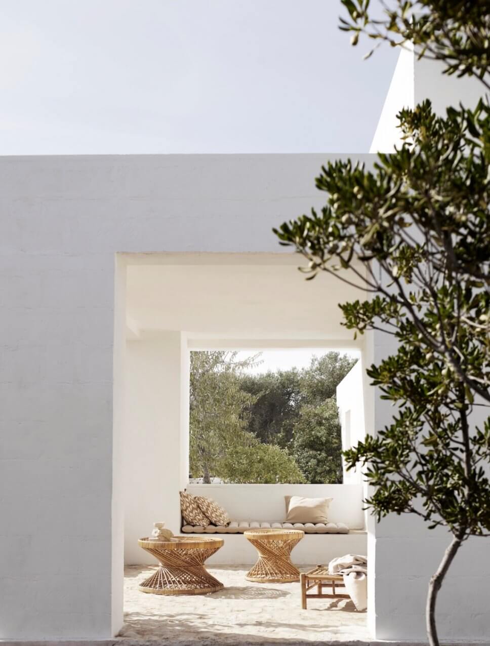 Mediterranes, weißes Haus mit Rattan-Tischen auf der Terrasse