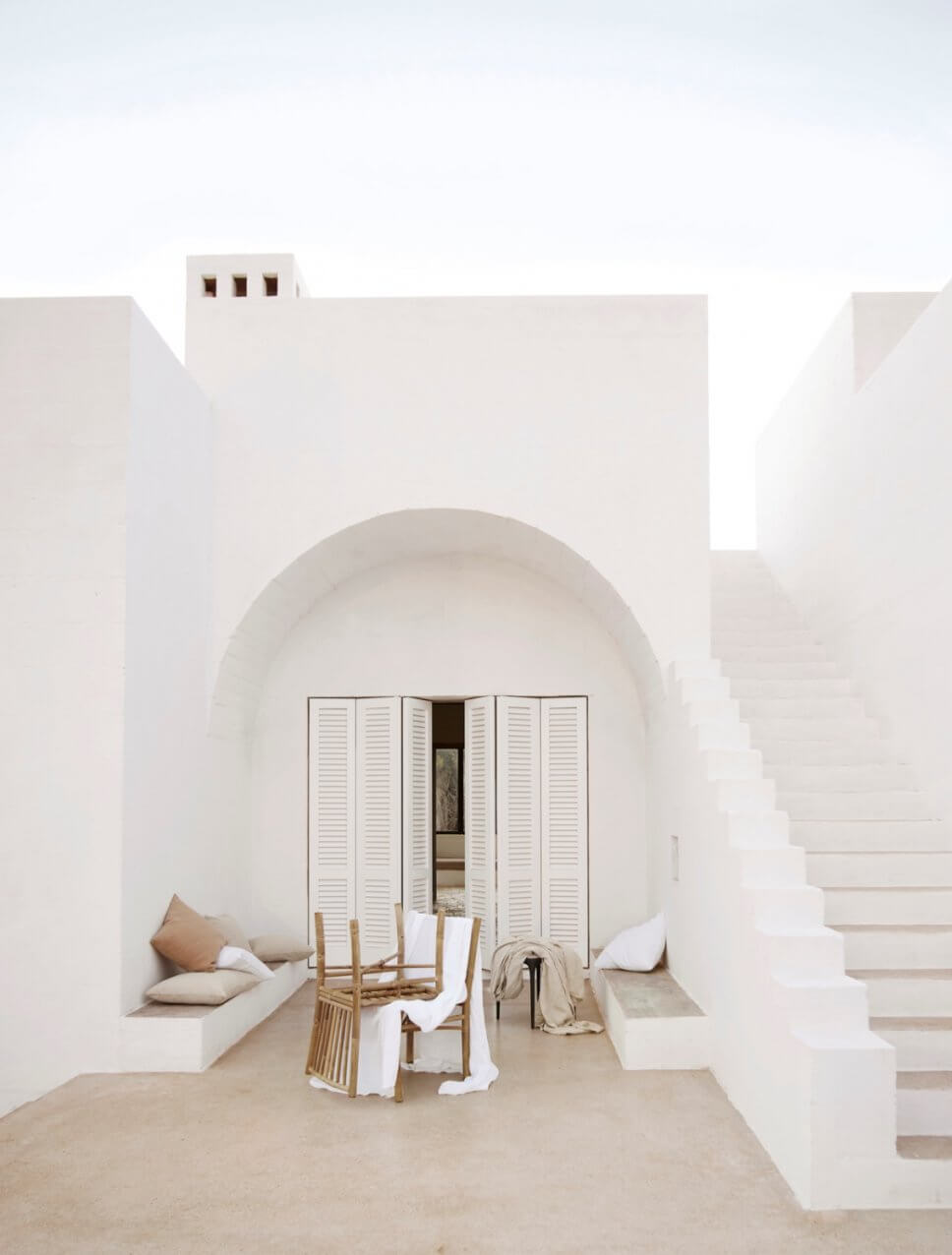 Mediterranes, weißes Haus mit Bambus-Gartenmöbeln auf der Terrasse