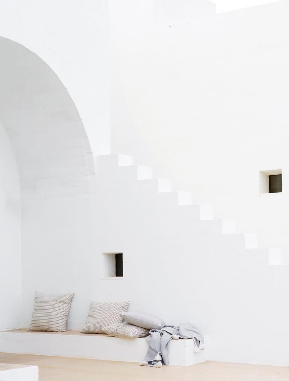 Mediterranes, weißes Haus mit Kissen auf einer Sitzbank
