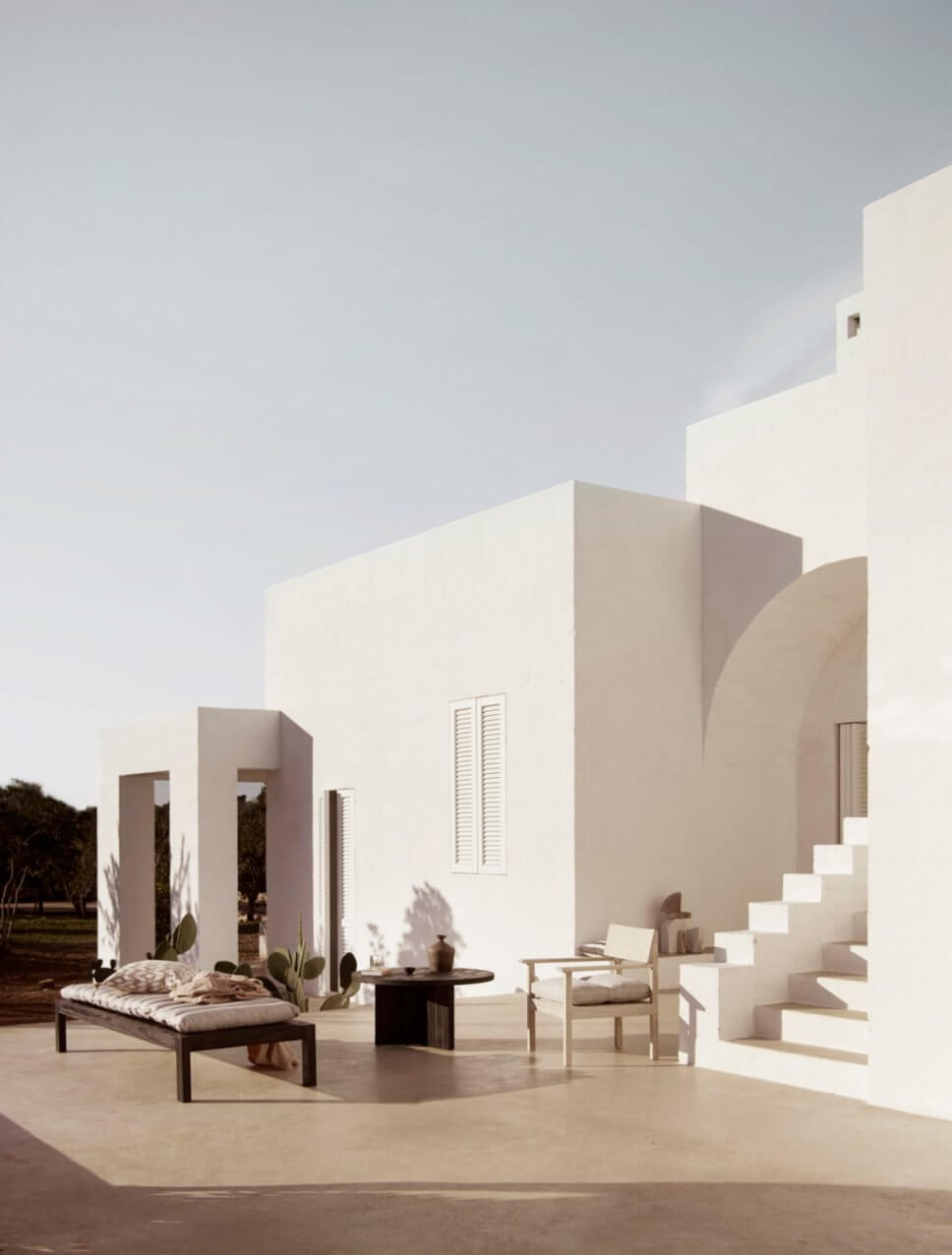 Mediterranes, weißes Haus mit Holz-Gartenmöbeln auf der Terrasse