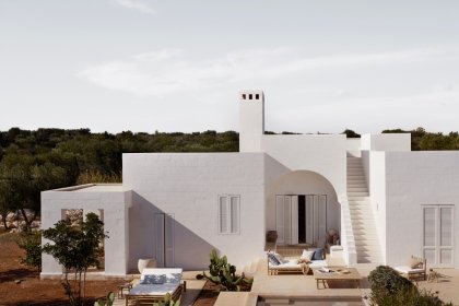 Mediterranes, weißes Haus mit Bambus-Gartenmöbeln auf den Terrassen