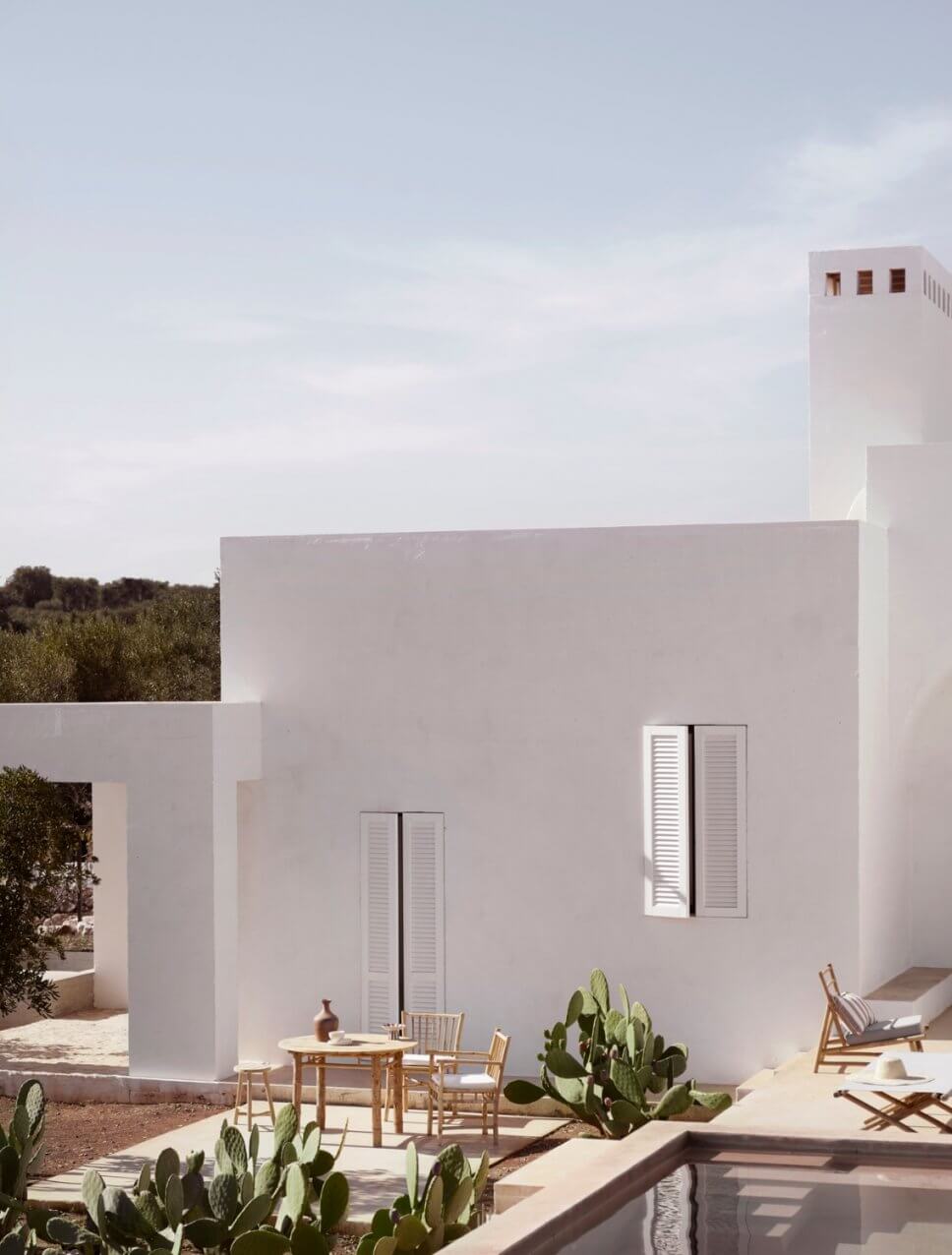 Mediterranes, weißes Haus mit Bambus-Gartenmöbeln auf den Terrassen