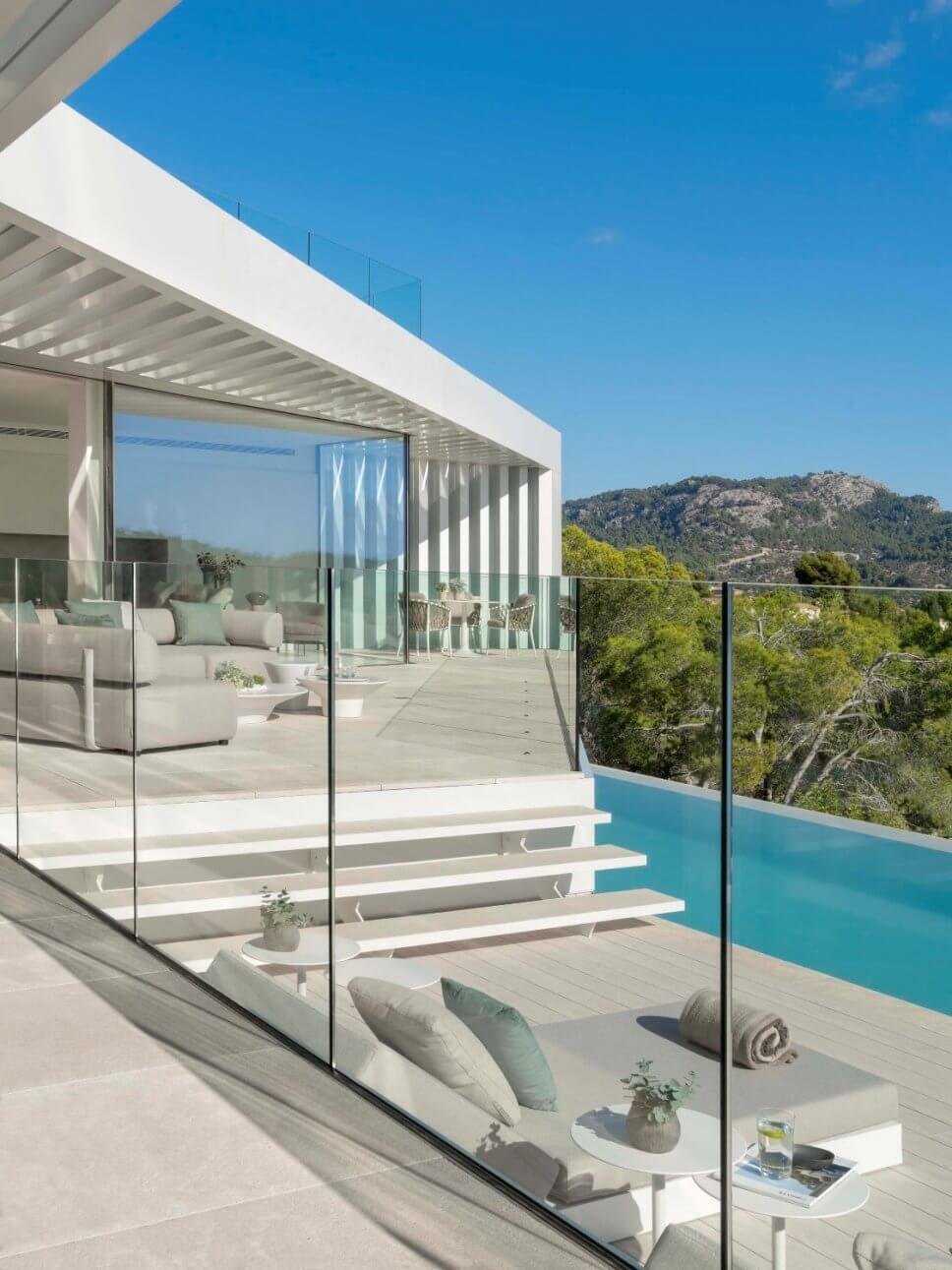 Terrasse mit zwei Sofas und zwei Liegen in moderner Villa mit Blick aufs Meer