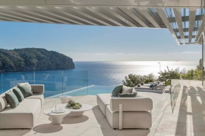 Terrasse mit zwei Sofas und zwei Liegen in moderner Villa mit Blick aufs Meer