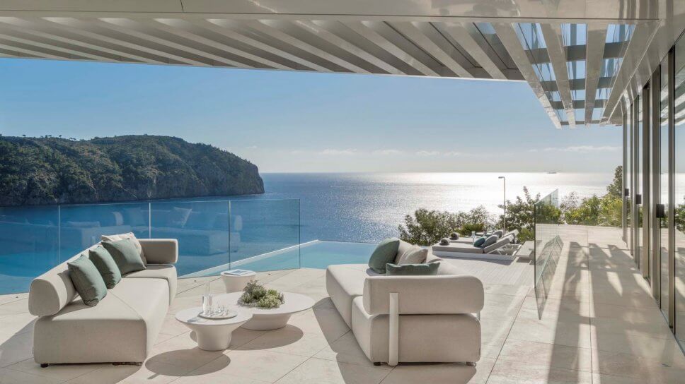 Terrasse mit zwei Sofas und zwei Liegen in moderner Villa mit Blick aufs Meer