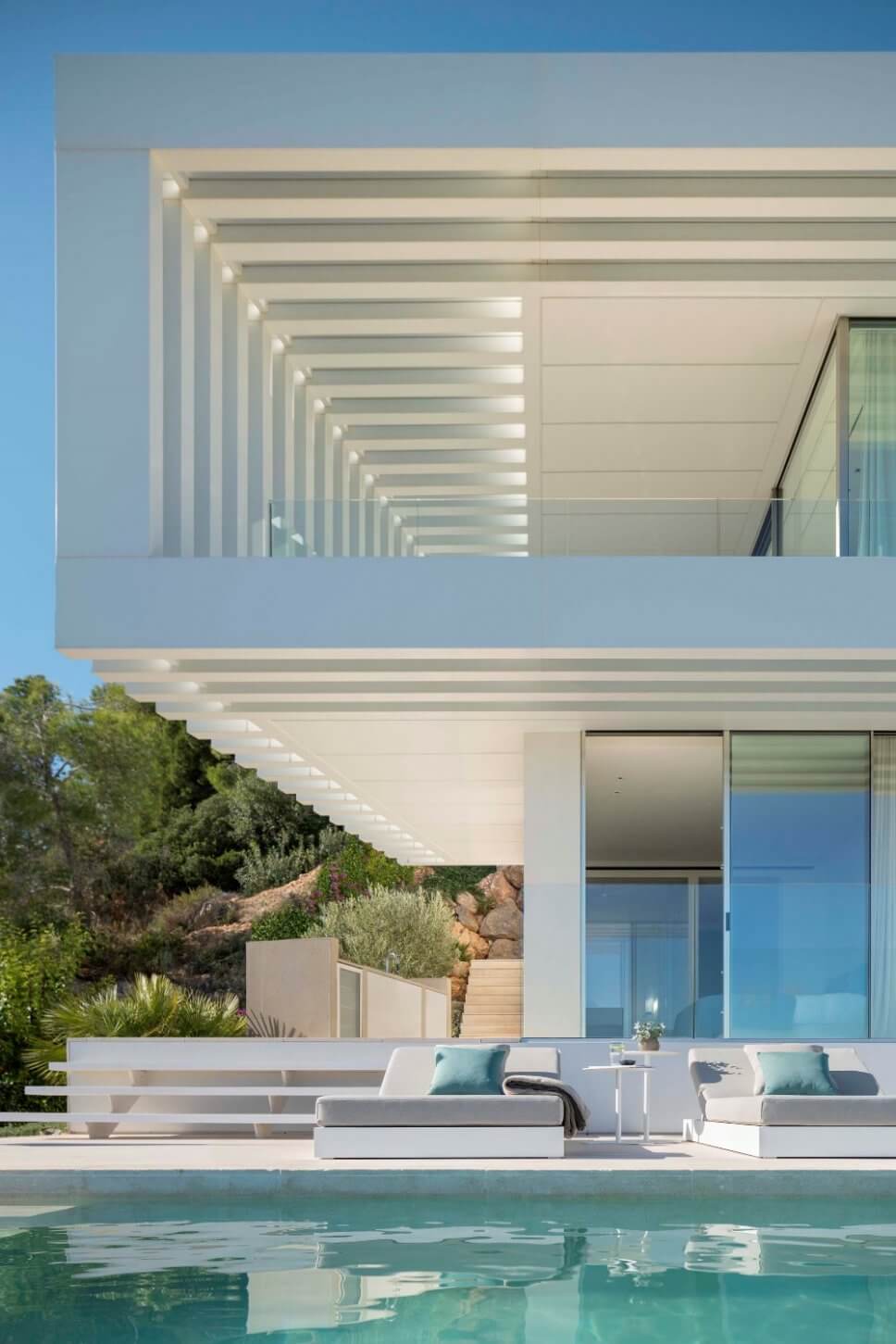 Terrasse mit zwei Liegen am Pool in moderner Villa