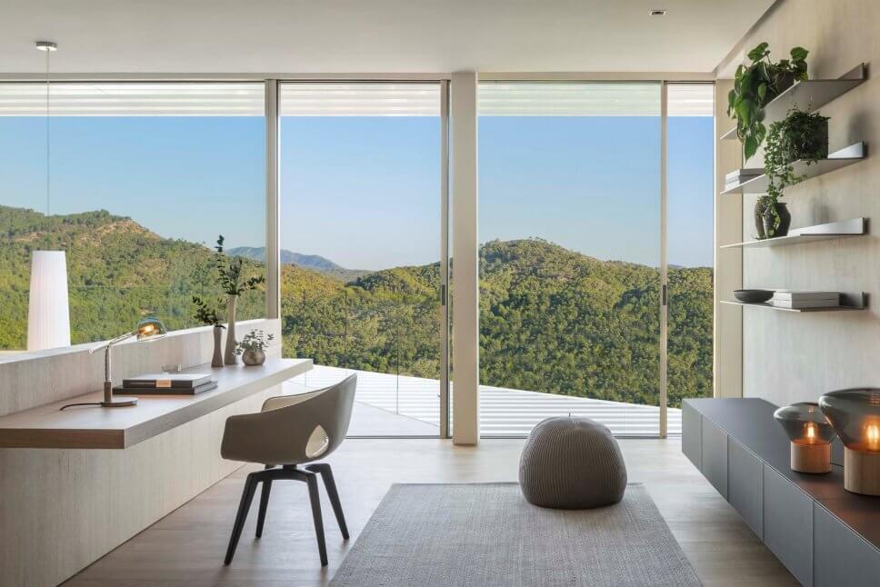 Stuhl vor Schreibplatte in moderner Villa mit Blick auf Berge