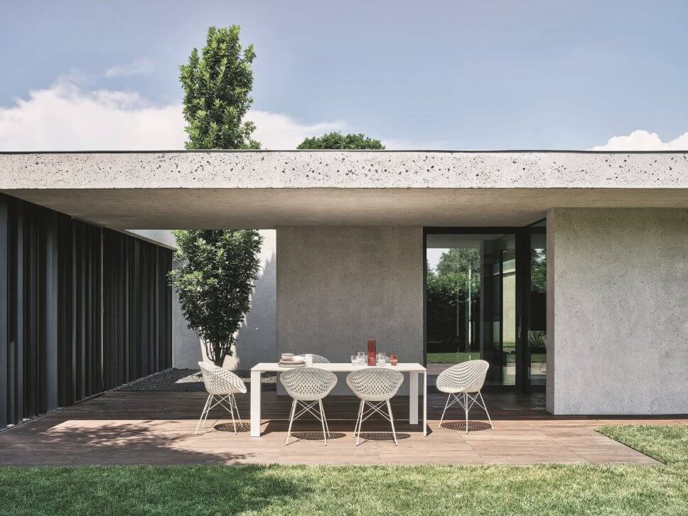 Moderne Gartenstühle stehen um einen Tisch auf Terrasse