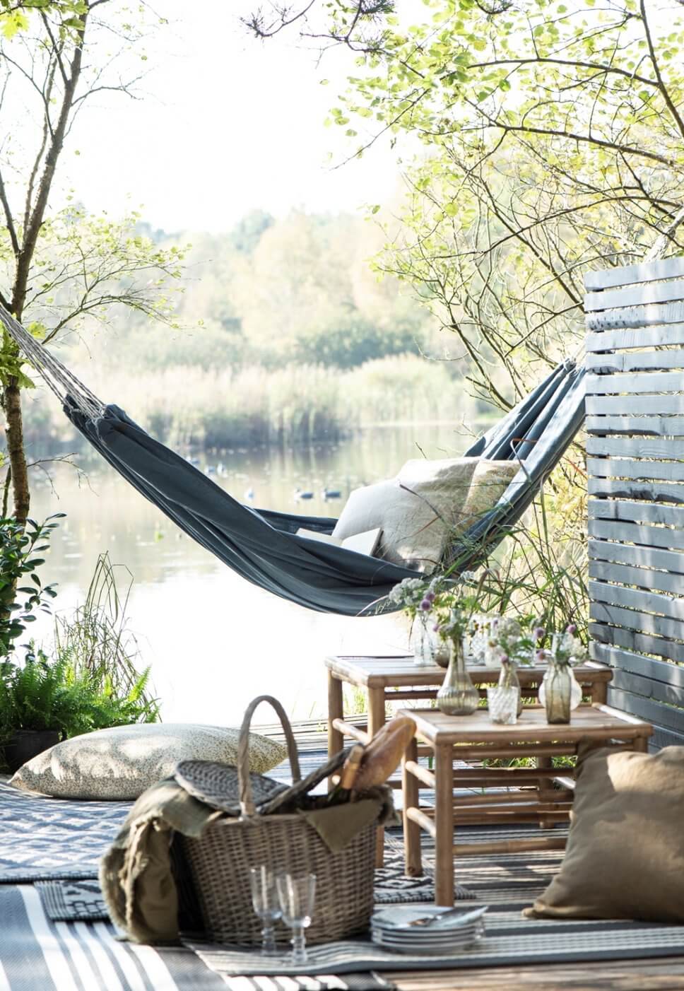 Hängematte mit vielen Kissen und Decken am See