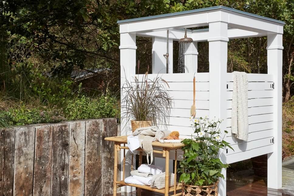 Bambustisch mit vielen Handtüchern vor hölzerner Gartendusche